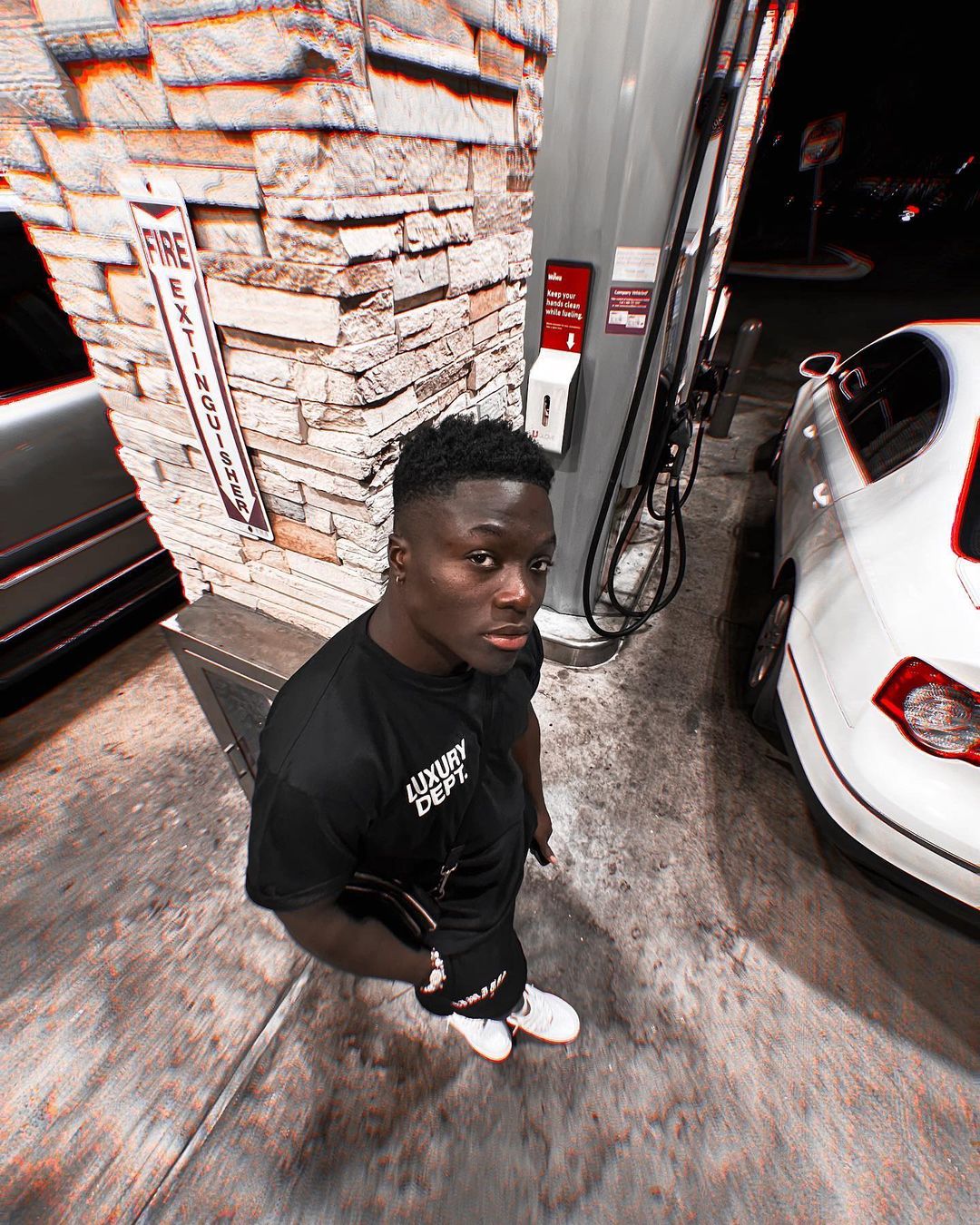 Call Me Manny posing outside at night in a black outfit